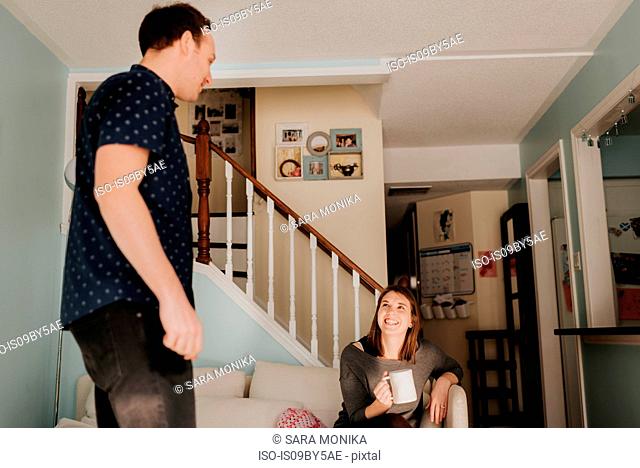 Mid adult couple in living room with mug of coffee