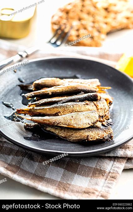 Smoked sprats on plate. Canned sea fish