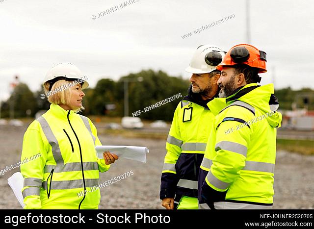 Engineers in reflective clothing looking at plans
