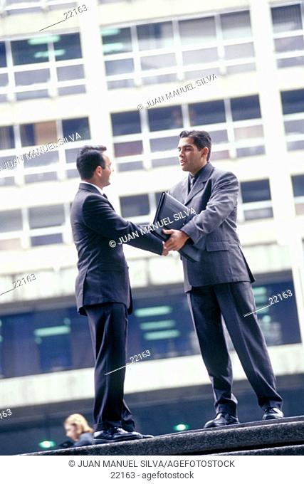 Businessmen shaking hands in the street