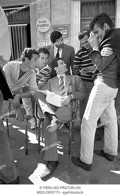 Italian director Pier Paolo Pasolini sitting and holding the script surrounded by some members of the crew on the set of the film Accattone