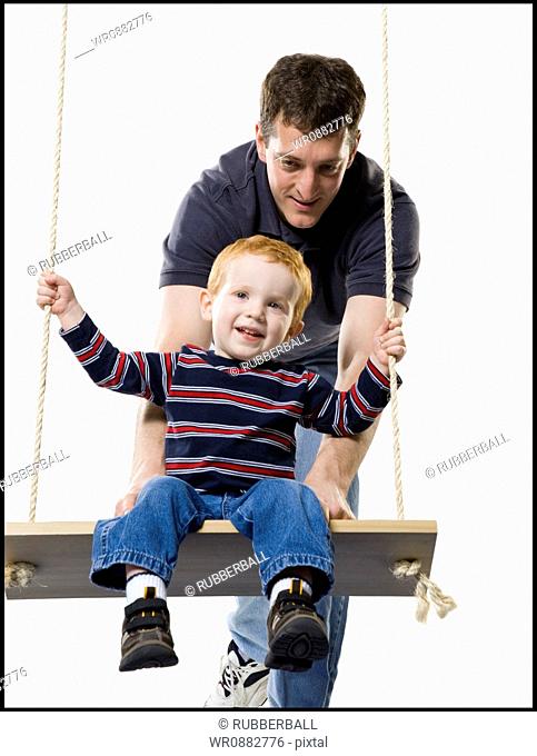 Father pushing his son on a swing