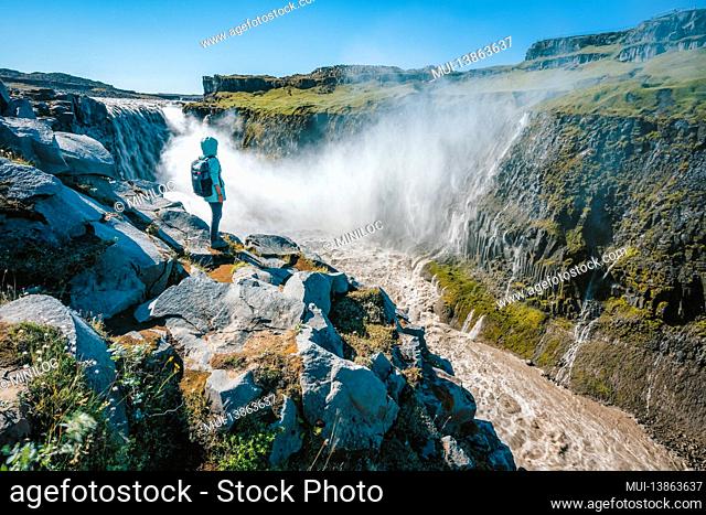 Woman on the cliff of Dettifoss most powerful waterfall in Europe, Iceland