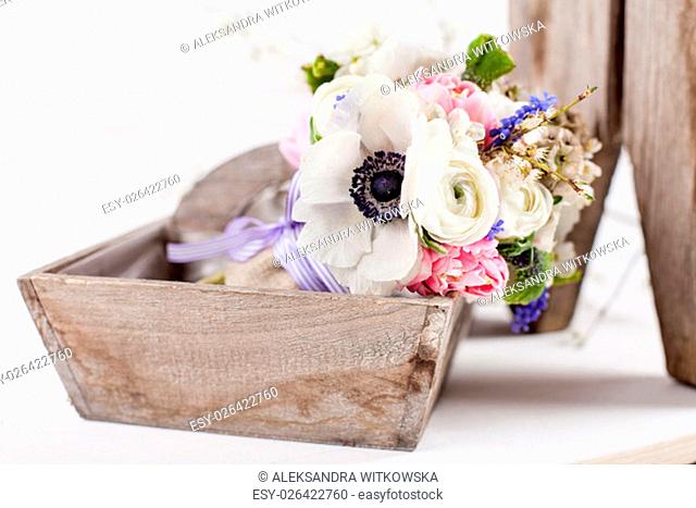 Bouquet from pink tulips, violet grape hyacinths, white anemones, violet veronica and white buttercup with violet ribbon lying in the old wooden basket with...