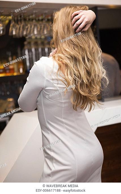 Rear view of pretty blonde girl posing hands in the hair