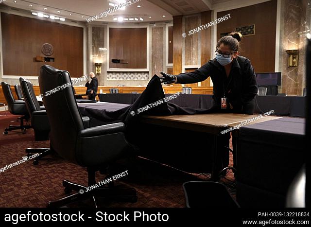 Workers change linens, wipe down chairs and microphones, and empty trash cans between Senate committee hearings in the Dirksen Senate Office Building on Capitol...