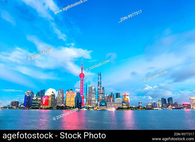 modern office buildings near illuminated orient pearl tower by river at twilight
