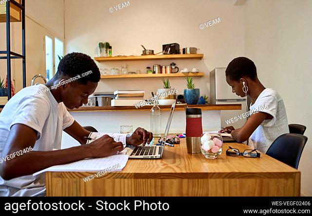 Young couple studying on table while sitting at home