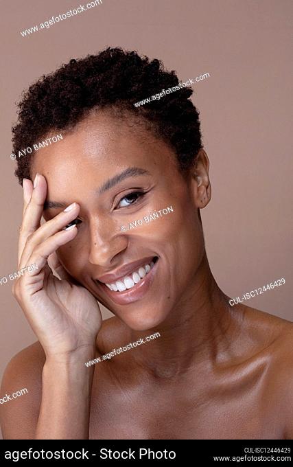 Studio portrait of smiling woman touching face