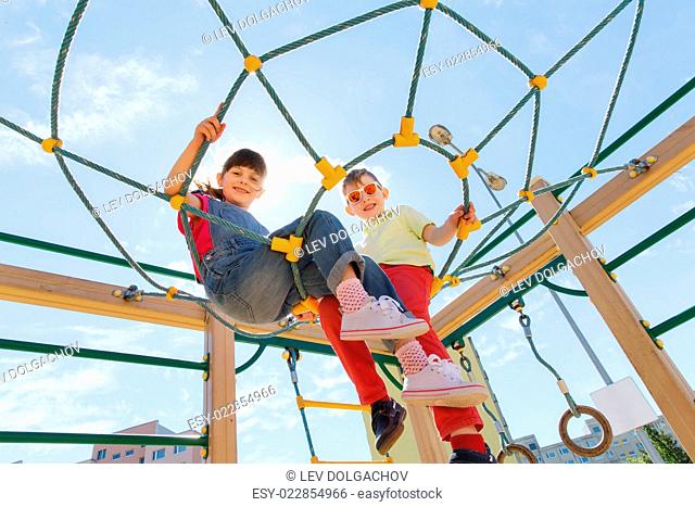 summer, childhood, leisure, friendship and people concept - group of happy kids on children playground climbing frame