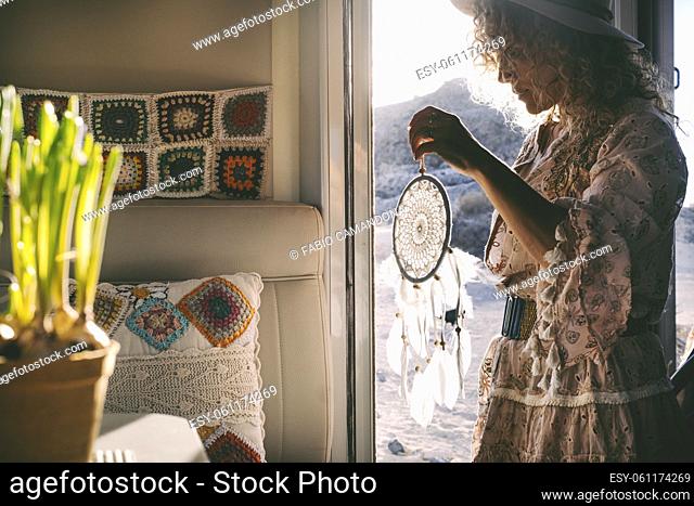 Boho dress style trendy woman on the camper van door with a hand made dreamcatcher. Alternative female people enjoying travel wanderlust lifestyle and summer...