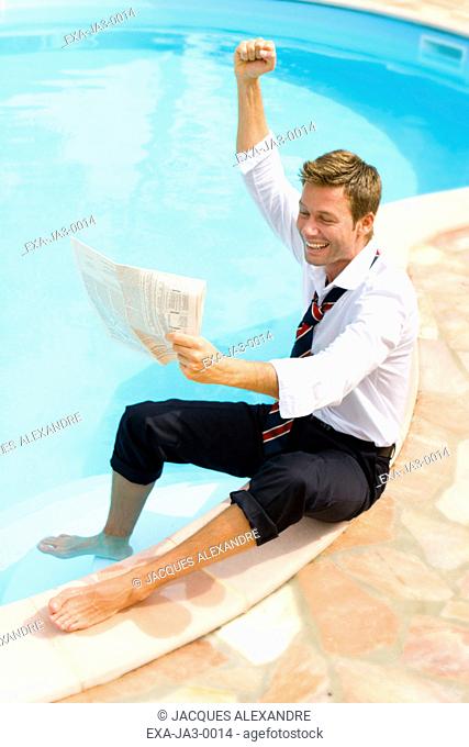 Businessman with foot in pool cheering and reading newspaper
