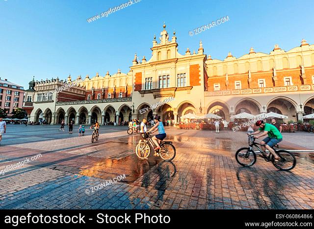 CRACOW, POLAND - June 29, 2016: The Cloth Hall, Polish Sukiennice. People cycling on the main market square. Old medieval town of Cracow is listed as UNESCO...