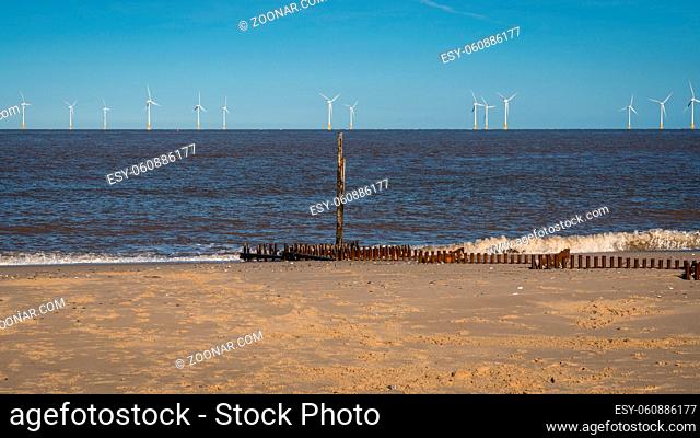 North sea coast in Caister-on-Sea, Norfolk, England, UK - with a wave breaker and wind turbines in the background