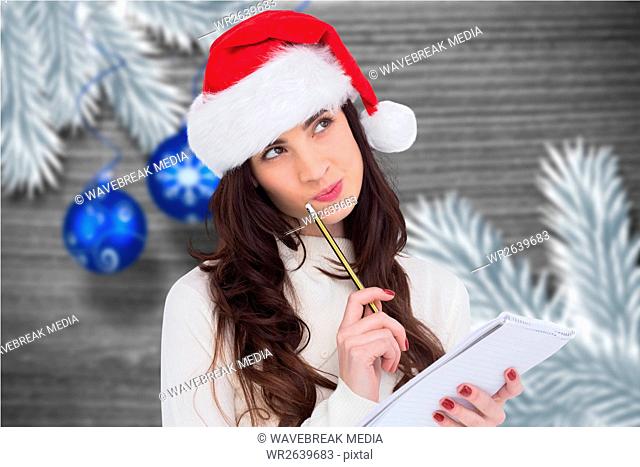 Thoughtful woman in santa hat making a wish list