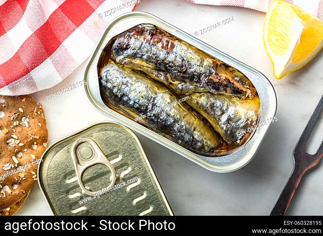 Canned sardines. Sea fish in tin can on kitchen table. Top view