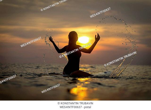 Indonesia, Bali, female surfer in the ocean at sunset