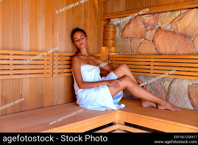 Caucasian young woman in a bathrobe relaxing in the sauna