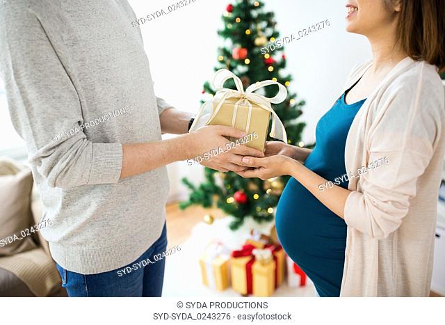 husband giving christmas present to pregnant wife