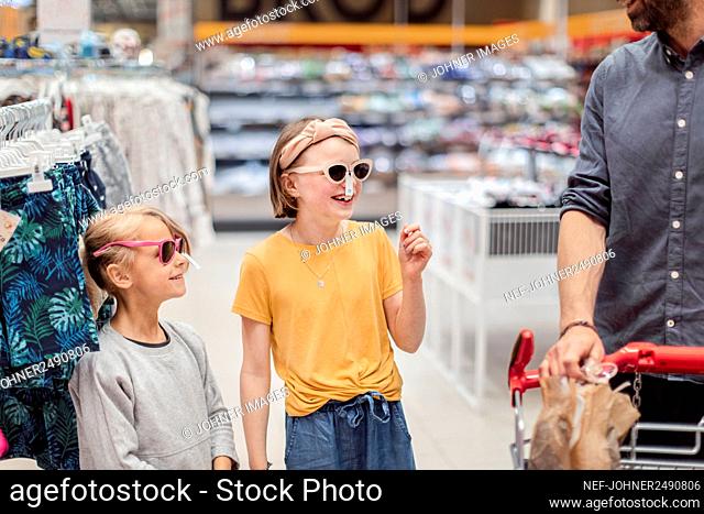 Smiling girls trying sunglasses in shop