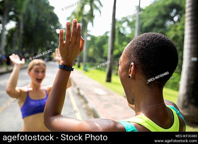 Cheerful friends giving high-five at footpath