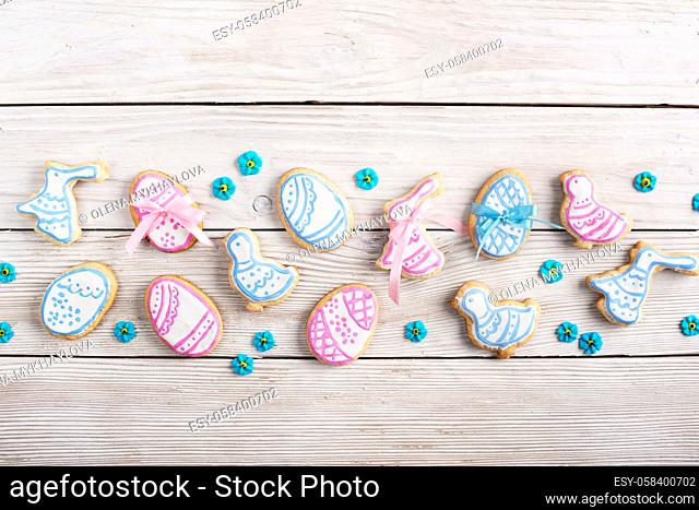 Easter frosted cookies in shape of egg chicken and rabbit on white wooden table background along with sugar sprinkles. Flat lay horizontal mockup