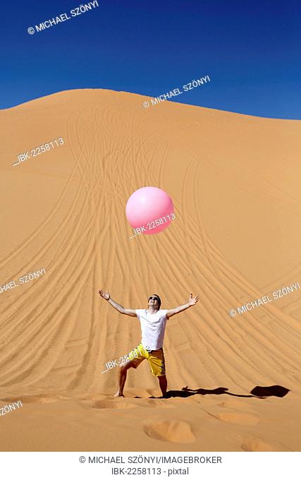 Lightness, man throwing up a large pink balloon in the desert, Coral Pink Sand Dunes State Park, near Kanab, Utah, USA