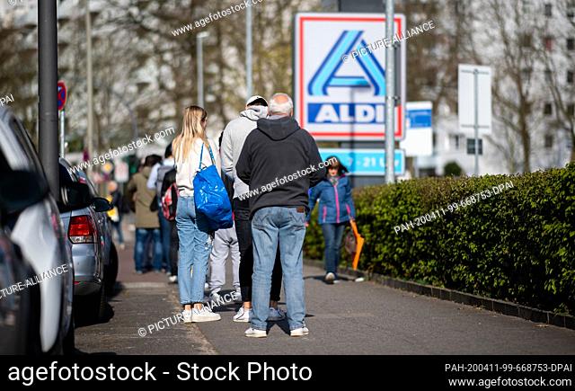 11 April 2020, Hamburg: People wait in a queue in front of an Aldi market. Photo: Daniel Reinhardt/dpa. - Hamburg/Hamburg/Germany