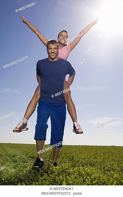 Young man carrying woman on back