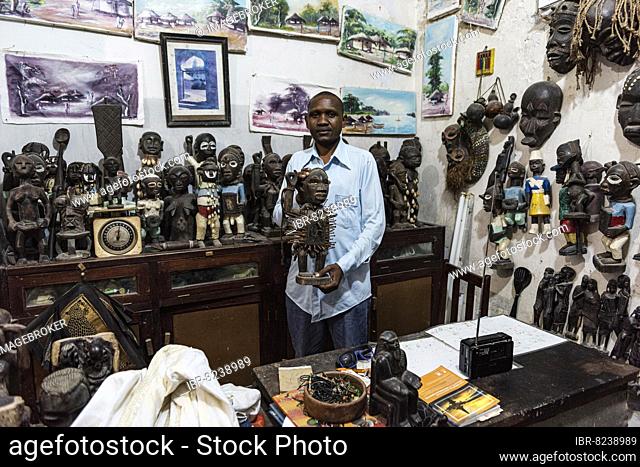 Verkäufer mit Holzfigur, Figuren und Masken aus Holz in einem Laden in Stone Town, Altstadt, Unguja, Sansibar, Tansania