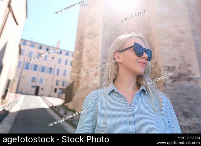 Photo of a beautiful blonde woman against the rustic church wall in France in Marseille