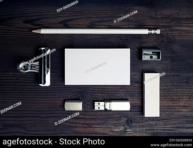 Blank stationery set on wooden background. Business card, pencil, eraser and flash drive. Top view. Flat lay