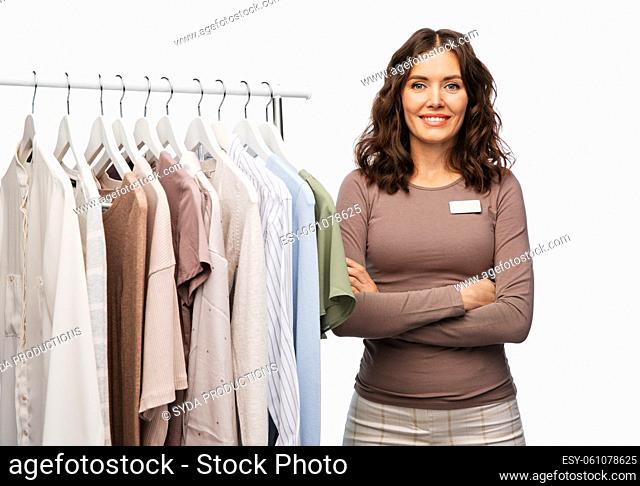 happy female shop assistant with clothes on hanger