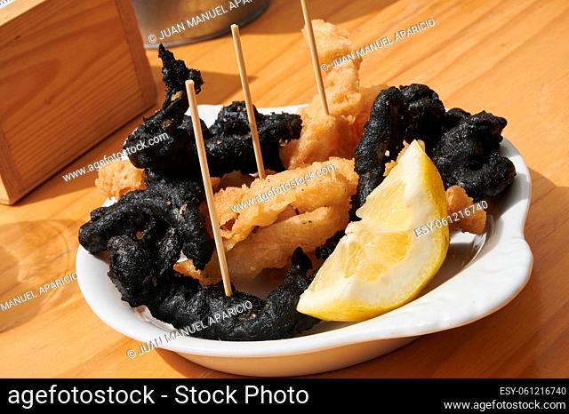 Traditional Spanish-style crispy squid, some fried with squid ink and served with a lemon wedge