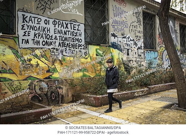 A woman walks past a house that is covered with graffitis in the Exarchia quarter in Athens, Greece, 19 November 2017. The lettering 'total resistance against...