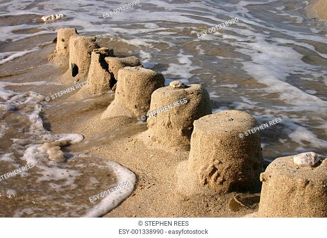 The ruins of a sand castle being swept away by the sea