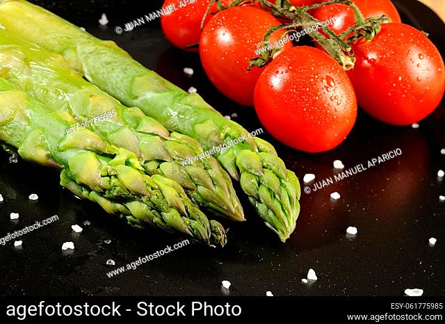 Delicious green asparagus whit maldon salt and cherry tomatoes on white background