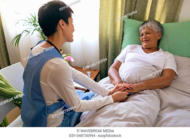 Female nurse taking care of senior female patient at retirement home