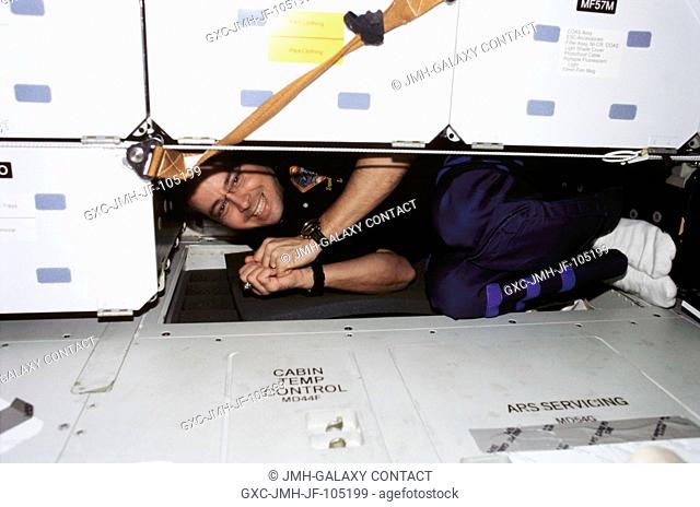Astronaut Daniel W. Bursch, Expedition Four flight engineer, squeezes under compartments on the middeck of the Space Shuttle Endeavour