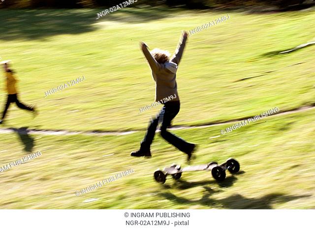 Girl jumping from a mountain board in a park