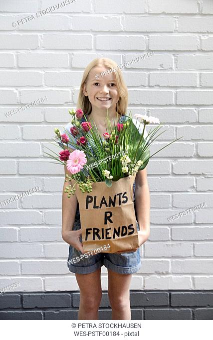 Portrait of smiling girl with paper bag of flowers