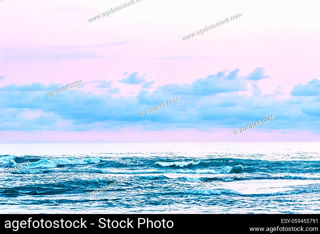 View of the blue sea shore with pink sunset light