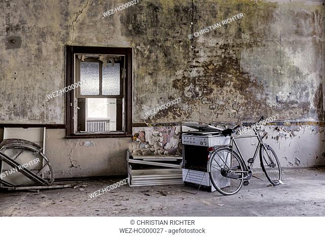 Germany, Thuringia, Erfurt, old bike and stove in abandoned room