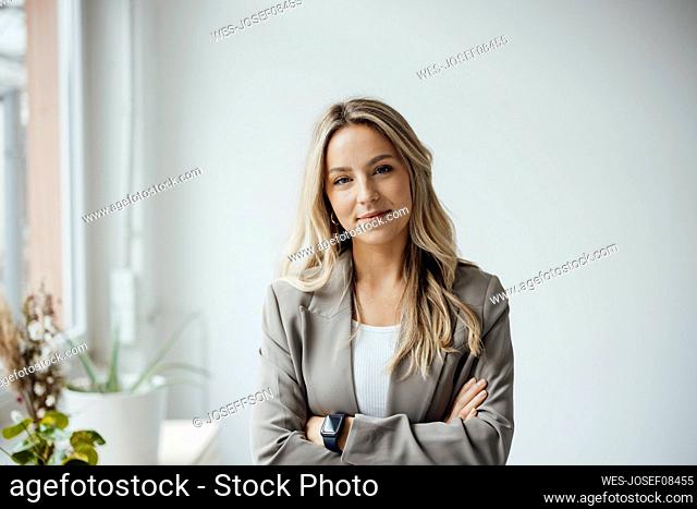 Smiling businesswoman standing with arms crossed in office