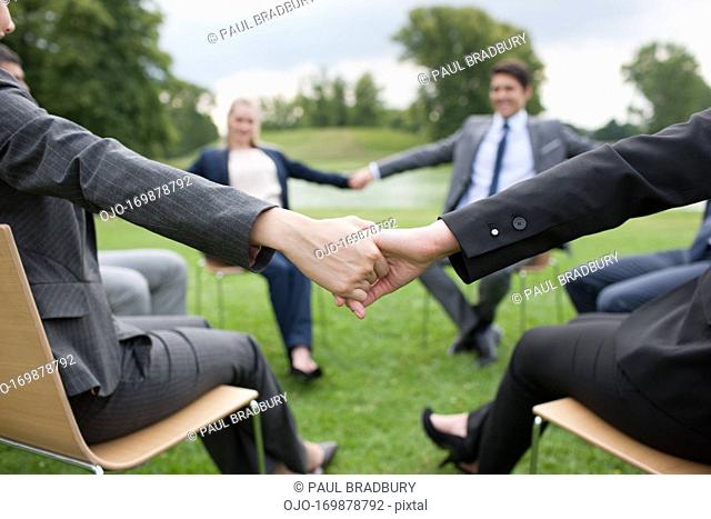 Business people holding hands in a circle outdoors