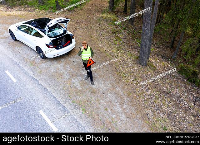 Man on side of road with broken down car