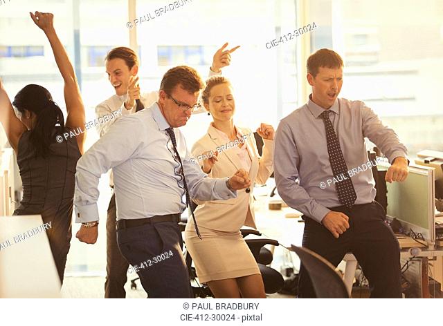 Enthusiastic business people celebrating and dancing in office
