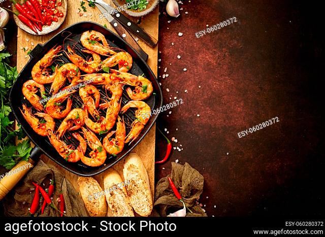 Tasty appetizing roasted shrimps prawns with spices on pan with ingredients on rusty background. Top View with Copy space