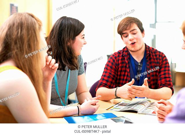 Female and male higher education students talking in college classroom