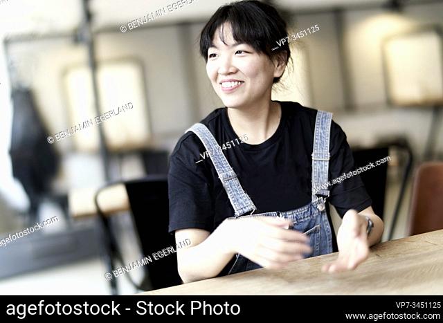 Korean woman sitting at table in cafe, moving hands